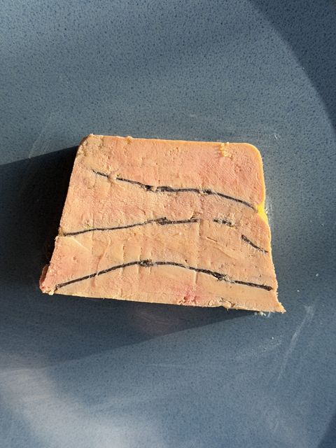 Sliced truffled foie gras terrine showing three veins of black truffle