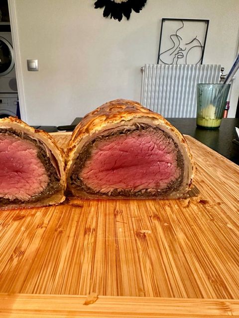Sliced beef Wellington showing rare beef, mushroom duxelles, ham, and puff pastry