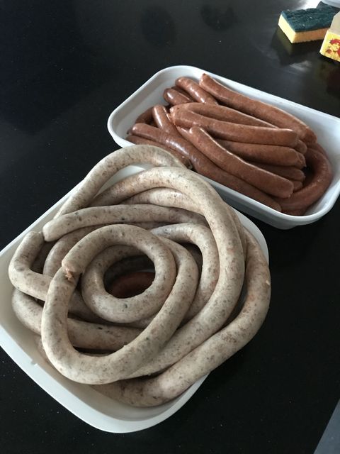 Two trays of fresh sausages — red harissa and pale pistachio