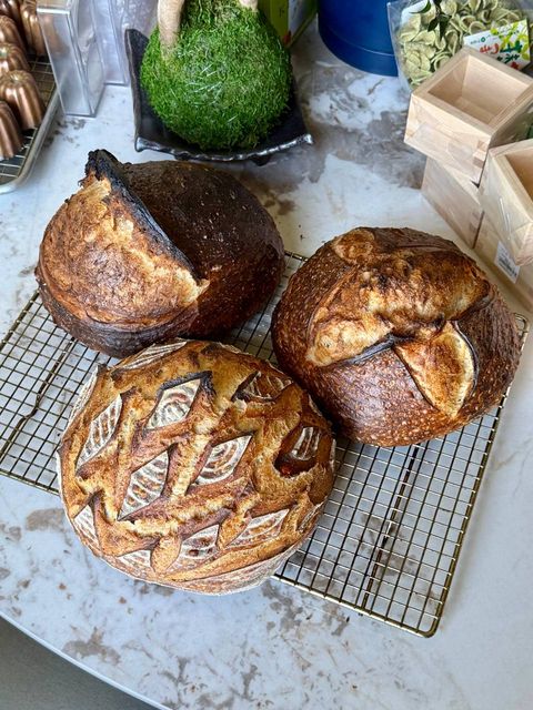 Three finished Tartine-style sourdough loaves cooling on a wire rack