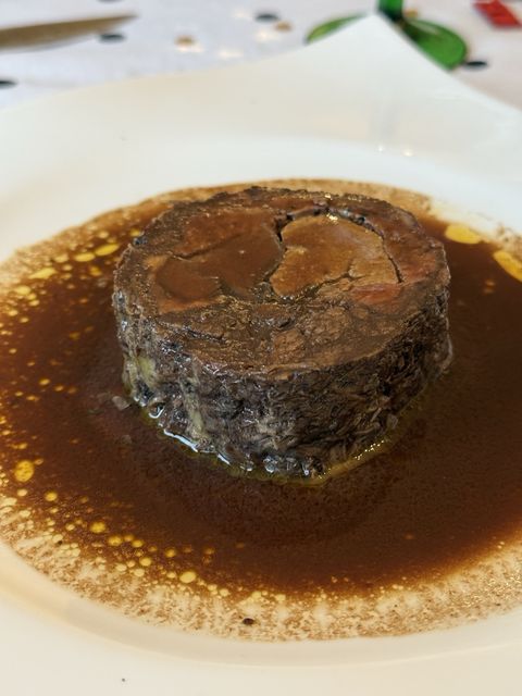 A slice of lièvre à la royale plated in its dark glossy sauce