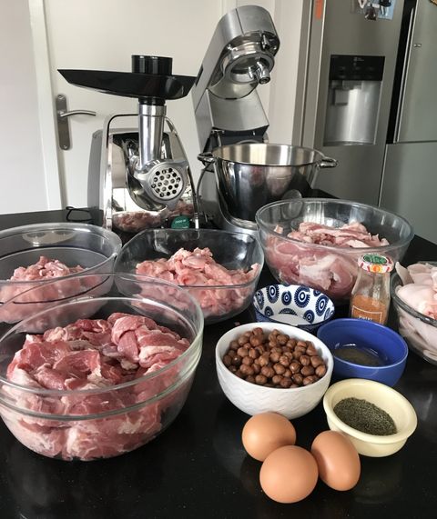 Rabbit pâté ingredients laid out with a meat grinder — cubed meats, hazelnuts, eggs, thyme and spices
