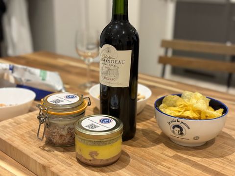Jars of homemade pâté with a bottle of red wine and a bowl of crisps