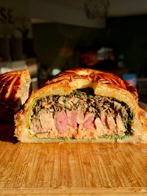 Cross-section of a game pithiviers showing puff pastry, greens, farce, foie gras, and game breast