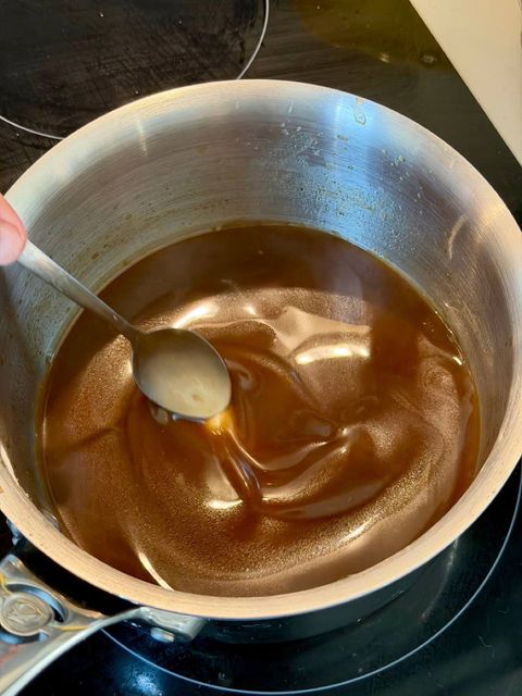 Glossy game jus reducing in a saucepan