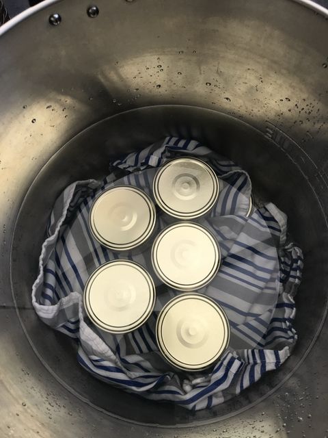 Filled jars on a towel, submerged in the pot